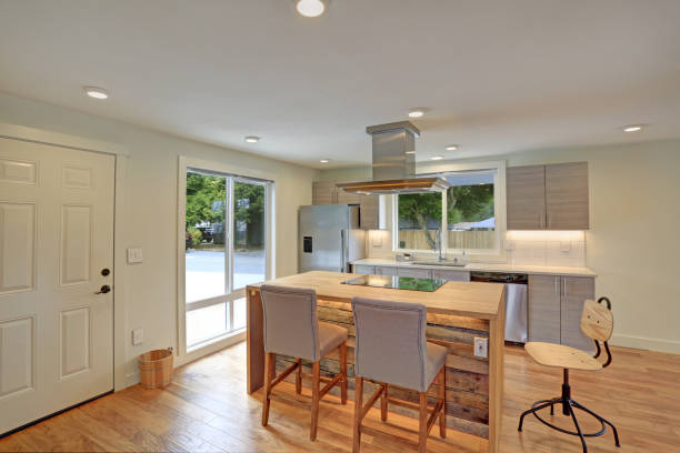 Newly remodeled kitchen boasts kitchen island with a hood, gray Shaker cabinets, quartz counters and modern stainless steel appliances.